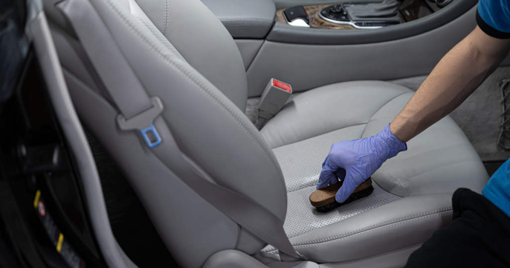 Aplicando hidratante para banco de couro preto em carro de luxo