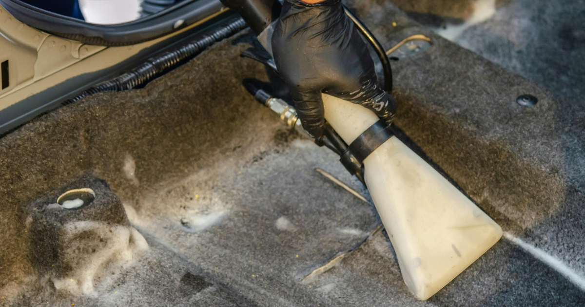 Uso de extratora profissional para demonstrar como limpar carpete do carro corretamente.